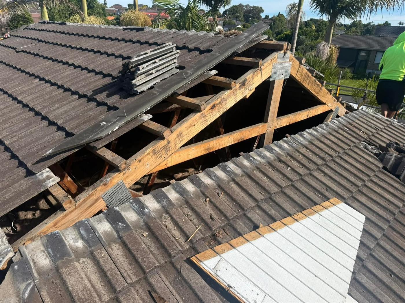 A tile roof opened up along a valley with the rafters and framing exposed underneath