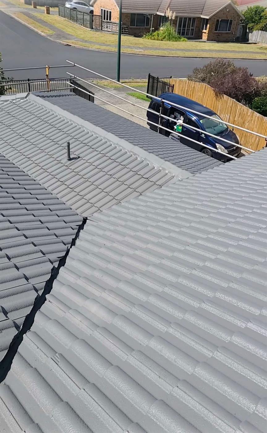 A restored concrete tile roof seen from the ridge looking down to the driveway and street